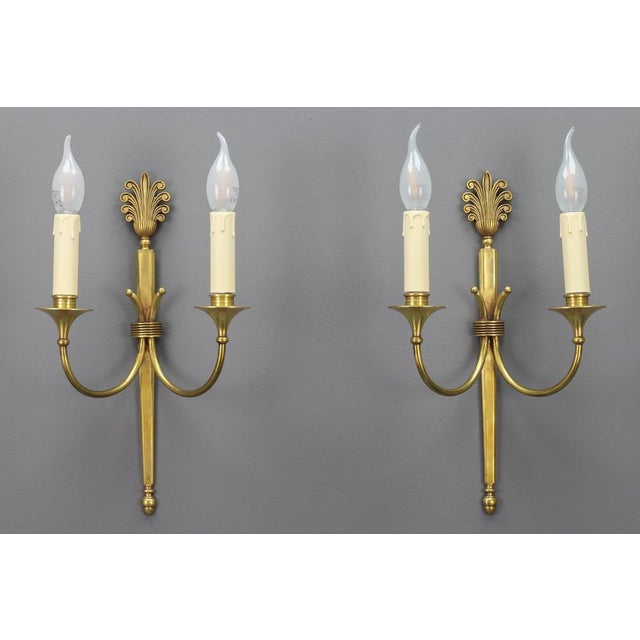 Pair of French Art Deco brass twin arm sconces from ca. 1930. This elegant pair of brass sconces has a beautiful brass...