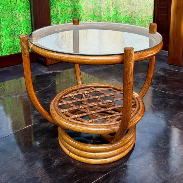 Vintage late 20th century round bamboo table with glass top. This piece has a bent bamboo base with rattan wrapped...