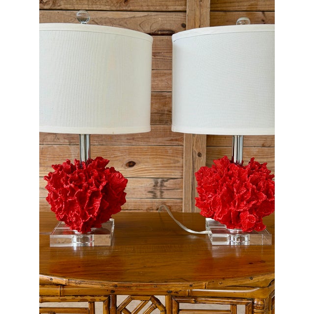 A striking pair of table lamps featuring sculptural faux coral bodies in vibrant red resin. The richly textured coral...