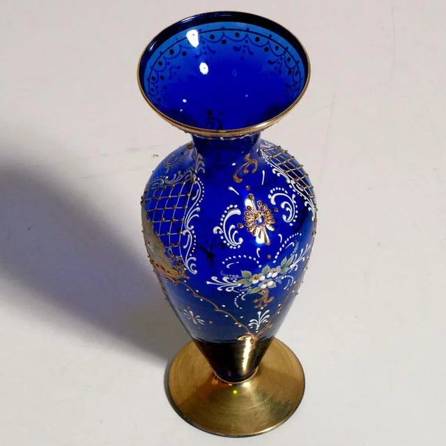 This amphora vase is made of blue glass and decorated in pure gold and polychrome hand-painted enamels.