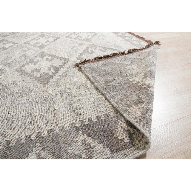 This gray wool rug features a hand knotted pile construction suitable for various home environments. Designed in the style...