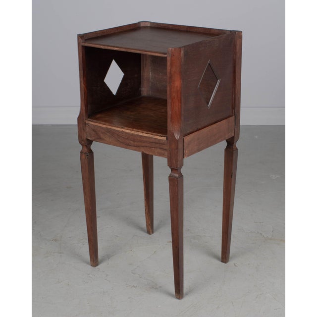 A Country French side table or nightstand made of solid mahogany, with open niche and pierced diamond shaped cut-outs on...