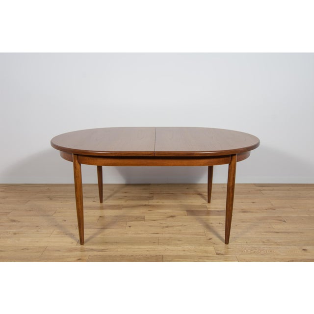 This is an oval-shaped teak dining table manufactured by G-Plan in the 1960s. The table has reinforced edges of the top....