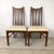 A set of six American mid-century walnut dining chairs — two armchairs and four side chairs — centered on a back design...
