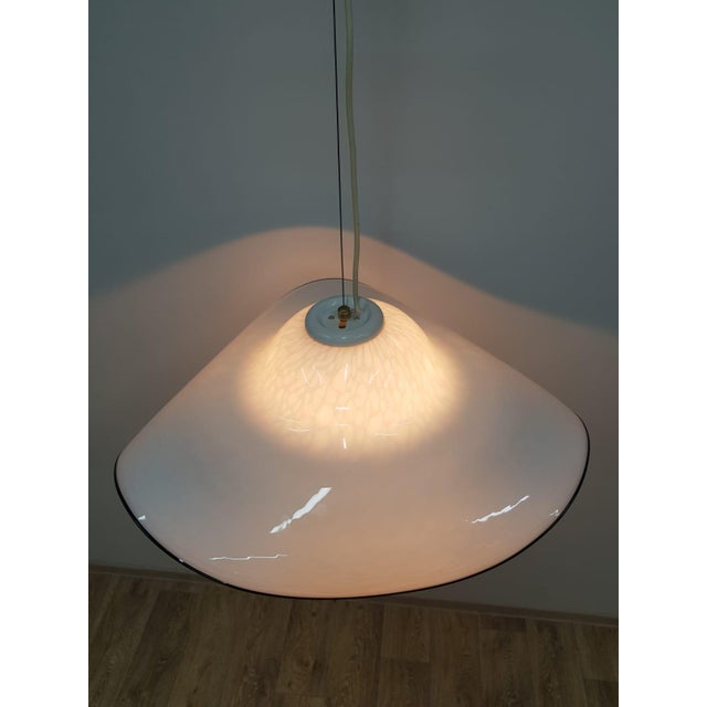 Murano hanging lamp from the 1960s and 1970s. Hand-blown white Murano glass with a black hat-shaped frame. The lamp is in...