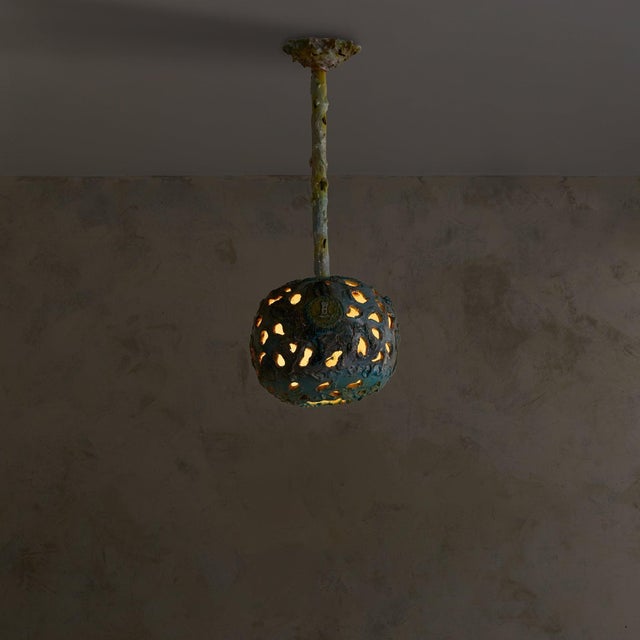 A rare 1970s Italian pendant by Umberto Ghersi—sculpted in ceramic with a cratered surface. The globe shade glows from...