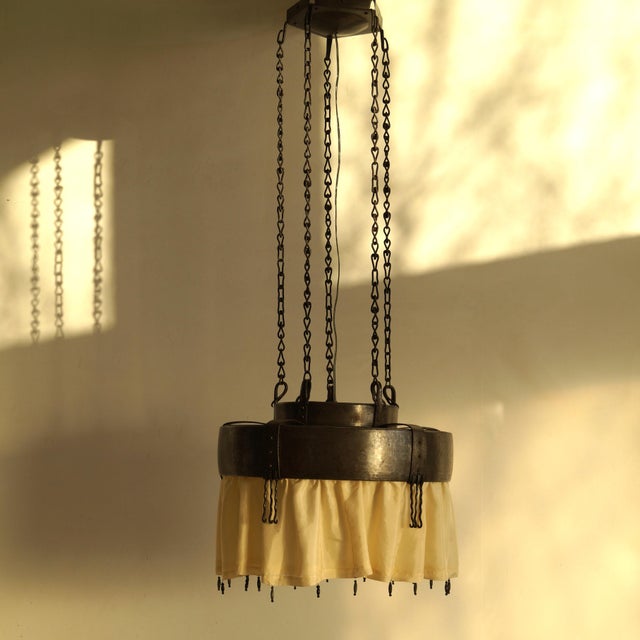 A rare amsterdam school chandelier with a hand-forged iron frame, stained and opaline glass crown, and a pleated silk...