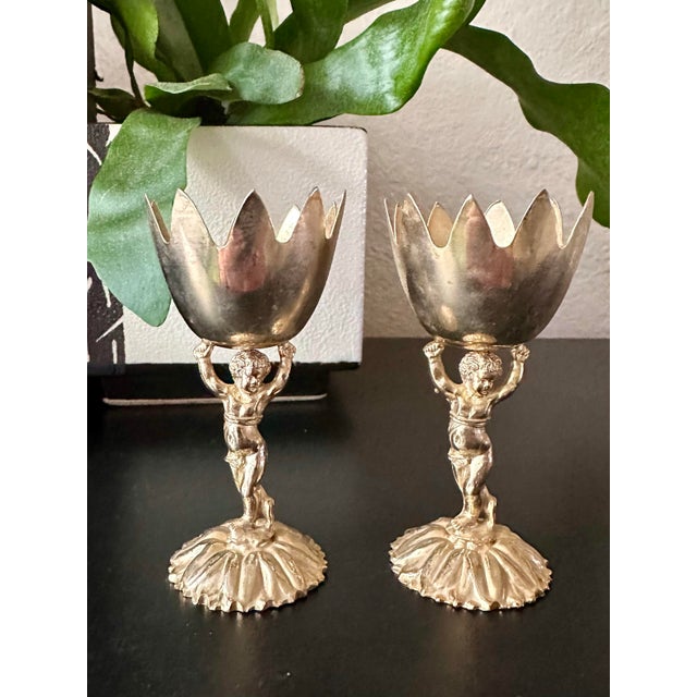 Elegant pair of vintage gold-toned cherub chalice stands, designed in a Renaissance-inspired style featuring detailed...