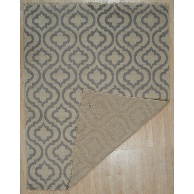 This gray wool rug features a hand knotted pile weave construction in the Rabat style. Produced in India, it serves as a...