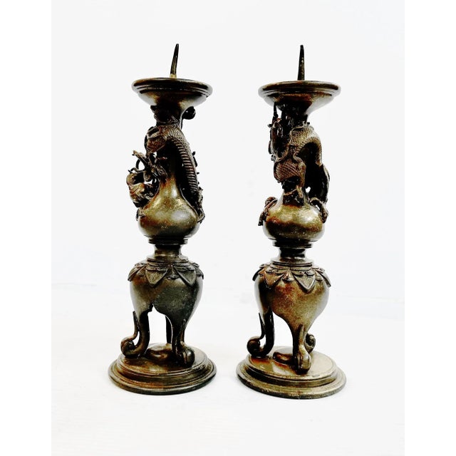 Pair of Chinese bronze pricket candleholders featuring the imperial dragon chasing the flaming pearl of immortality. These...