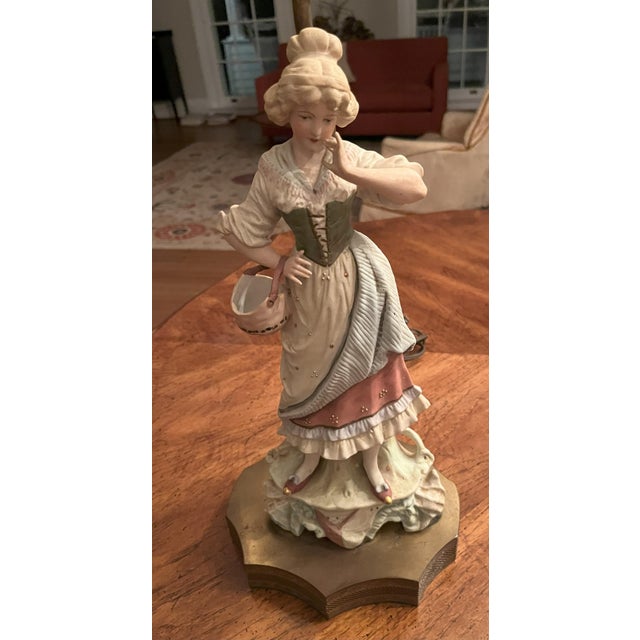 This vintage figurine woman with basket table lamp is a unique and charming addition to any home decor. Made from biscuit...