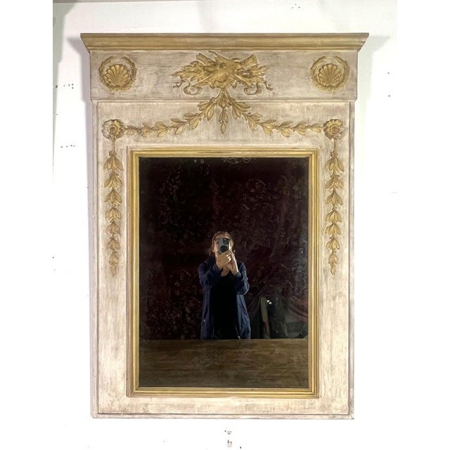 Pair of rectangular neoclassical style mirrors. The mirrors are painted in a cream color, accented with gold detailing....