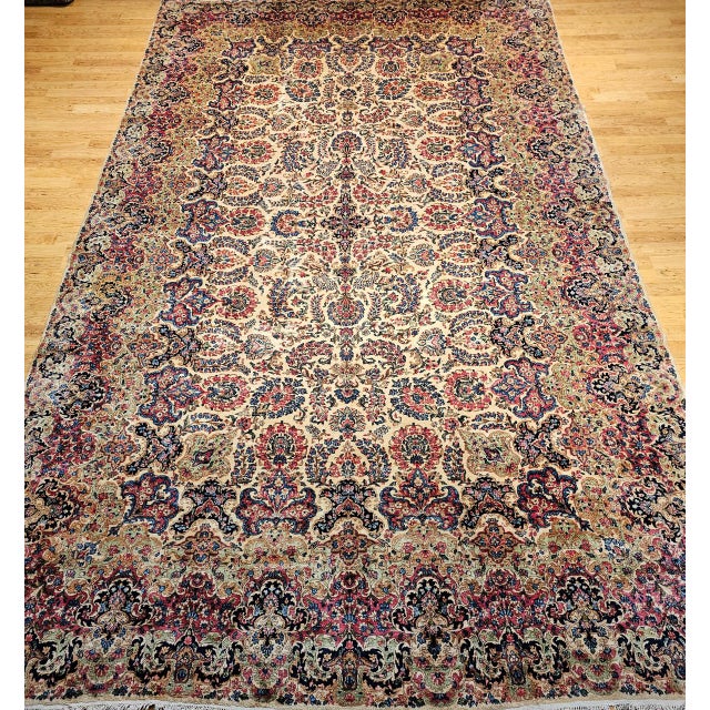 Step into timeless elegance with this vintage oversized Persian Kerman rug, handwoven in the early 1900s. Featuring a...