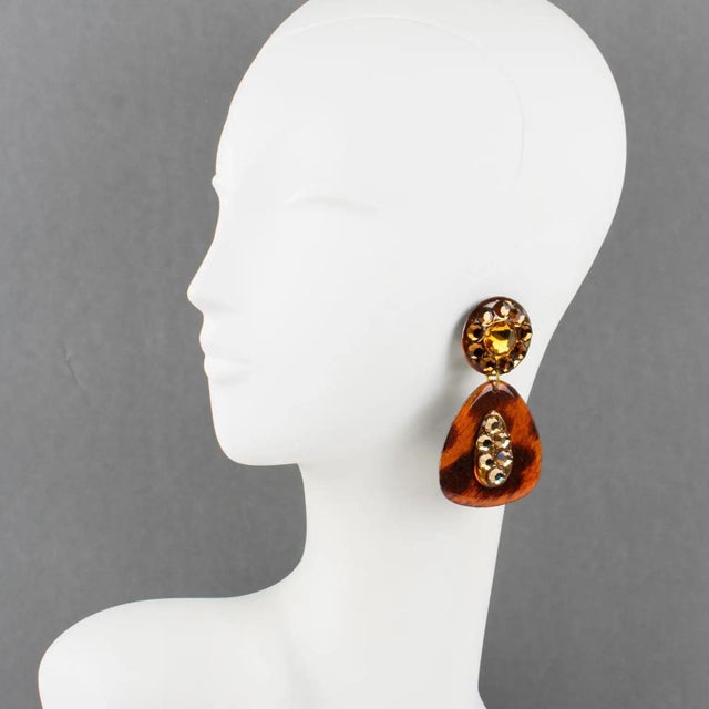 Those fabulous Lucite dangling clip-on earrings boast a chandelier shape with a geometric carved design in luminous amber...