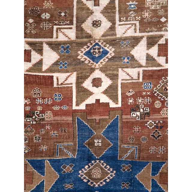 A vintage Caucasian Kazak accent rug with a geometric tribal design of 2 blue 8-point stars forming arrowheads and 1 cream...
