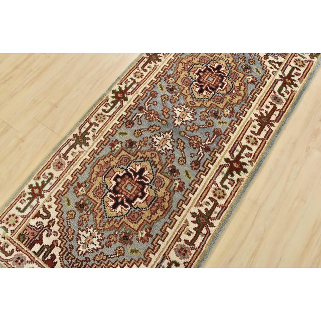 A traditional tribal Heriz runner hand-knotted with an all-wool pile on a cotton foundation. This oriental rug features...