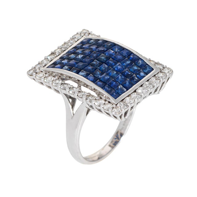 Stylish contemporary sapphire & diamond square cocktail ring crafted in 18 karat white gold. The invisible setting is a...