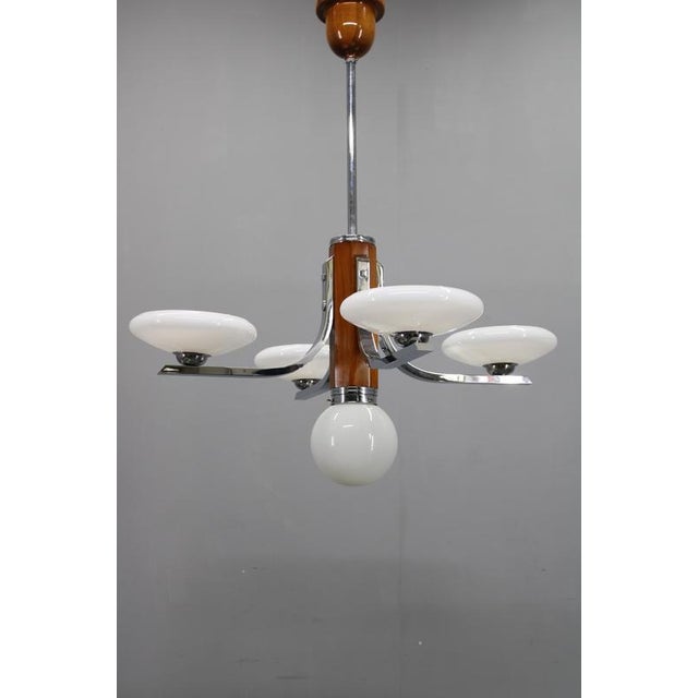 Elegant art deco chandelier produced in 1930s czechoslovakia, combining chrome-plated metal, walnut wood accents, and five...