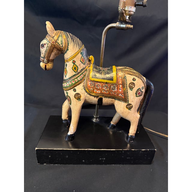 Whimsical mid-century table lamp featuring a beautifully carved and hand-painted wooden horse adorned with intricate folk-...