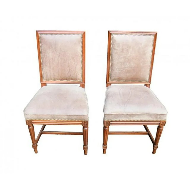 Set of Jansen manner Louis XVI style walnut wood dining side chairs with distressed brown leather seats and backs.