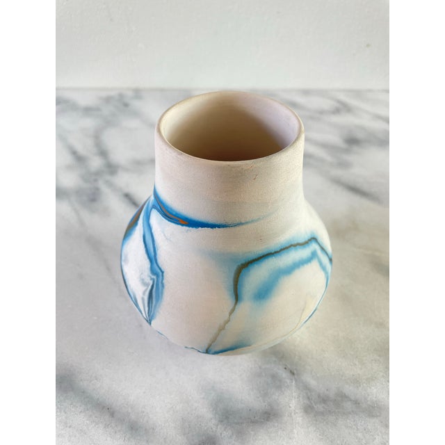 A vintage Nemadji ceramic pot with blue swirl over white body.