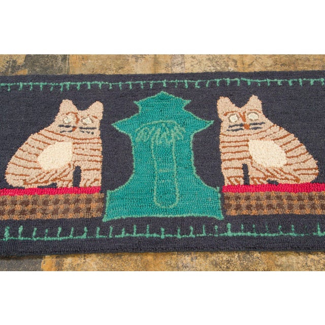 Hand-hooked in wool, this 2x4 contemporary pictorial rug showcases a dark charcoal ground with two striped cat figures...