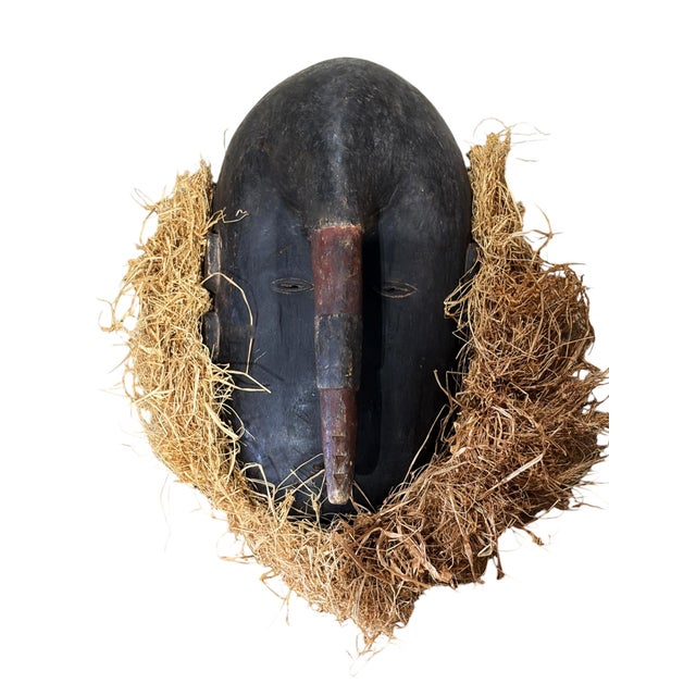 Vintage Ligbi mask with raffia from the Djimini people of Ivory Coast. This striking piece combines human features with...