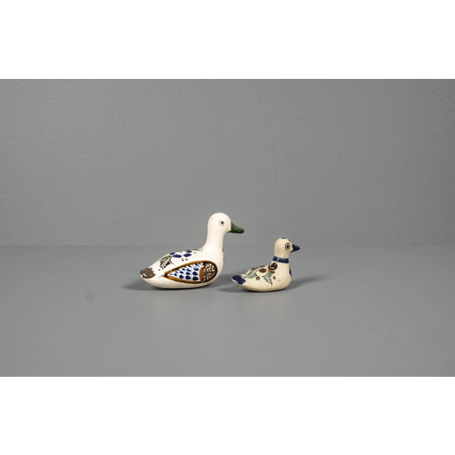 Decorative set of two glazed ceramic duck figures, consisting of one larger and one smaller piece. The ducks feature warm...
