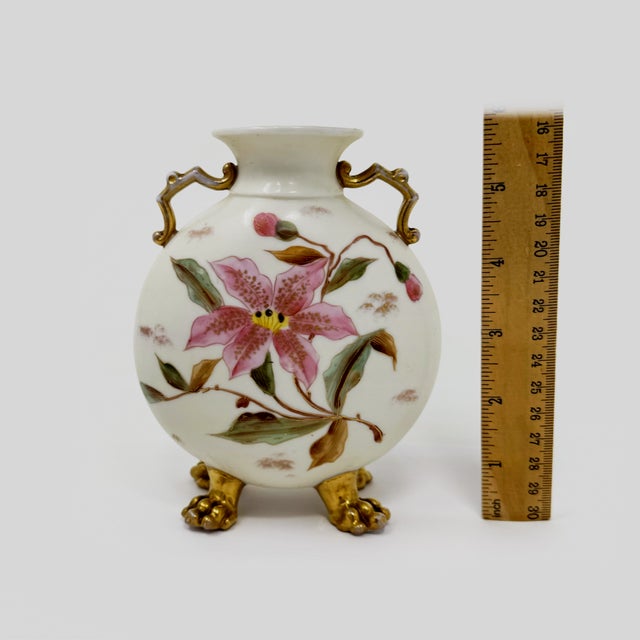 This fine antique Rudolstadt porcelain vase features a flattened round moon-flask body with elegant dual scroll handles...