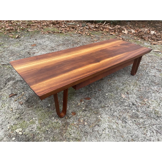 A low table or bench designed by Edward Wormley for Dunbar, constructed of solid, sap grain walnut planks with legs of...