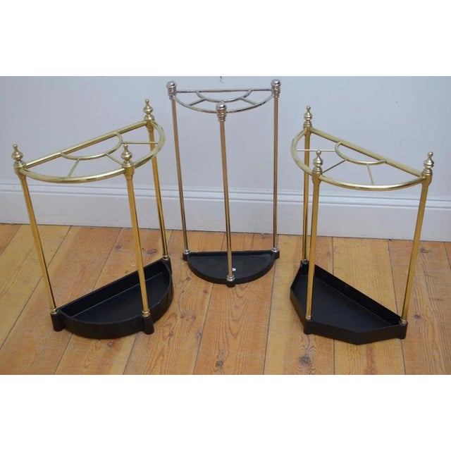 English half moon umbrella stand in brass, having five divisions with decorative finials and black drip tray with dog...