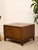A handsome vintage walnut nightstand featuring three spacious drawers, warm wood grain, and distinctive brass campaign-...