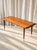 Elegant Mid-Century Modern coffee table, circa 1960, combining warm-toned teak with refined brass details. The elongated...
