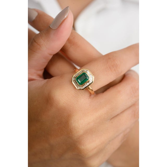 This 18k gold statement ring showcases an octagon-cut center emerald, surrounded by a dazzling baguette-cut diamond halo....