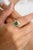 This 18k gold statement ring showcases an octagon-cut center emerald, surrounded by a dazzling baguette-cut diamond halo....