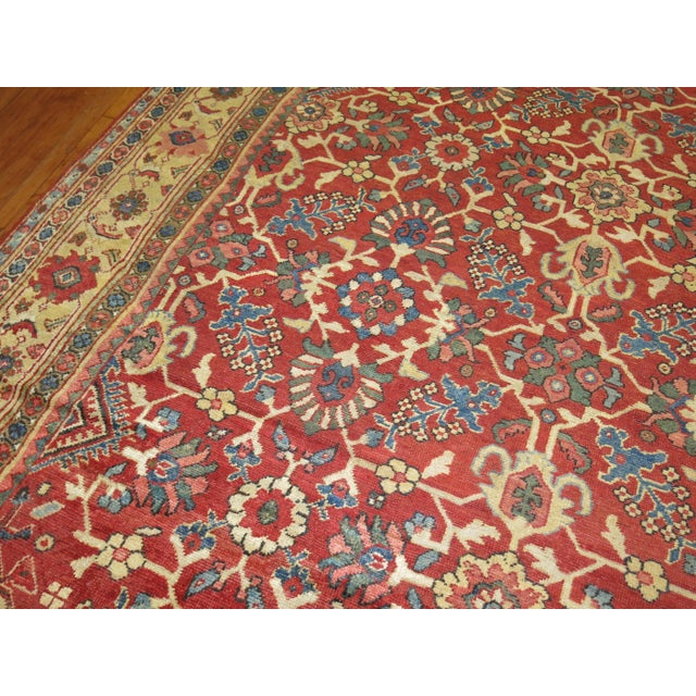 Room size Persian antique Mahal room size rug featuring an all-over repetitive design on a red field and beige/ivory...