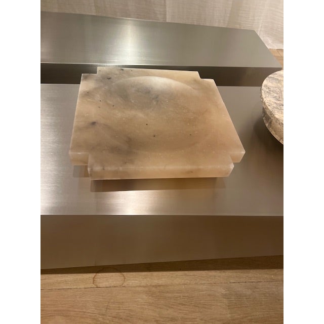 The Kros Tray by Michael Verheyden in Alabaster Tabac is carved from solid stone, showcasing warm, translucent tones and...