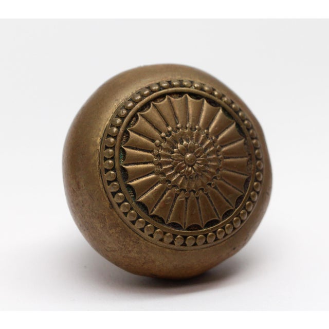 Bronze doorknob with a radial design. The manufacturer and date of creation is unknown. There is a dent on the side. The...