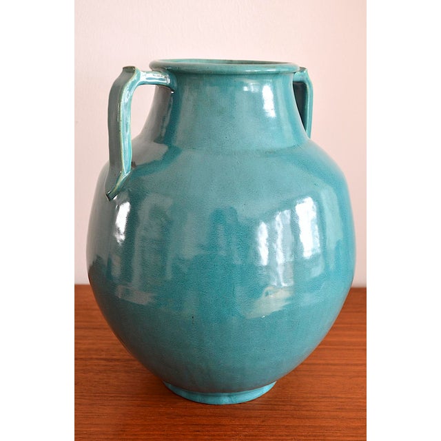 A beautiful, hand-thrown ceramic vase in the Art Deco style. The vase is made of reddish ceramic with a turquoise glaze.