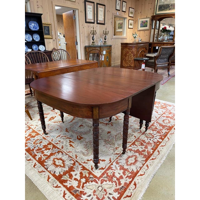 This is a graceful pair of antique mahogany drop-leaf dining tables that can be used individually or joined to form a...