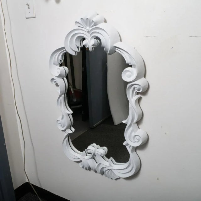 Carved wood mirror with scrolled "ribbon" surround featuring a plaster-like finish.