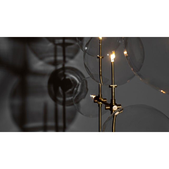 An array of ethereal glass globes floats weightlessly around a free-standing geometric lattice. The mouth-blown spheres...