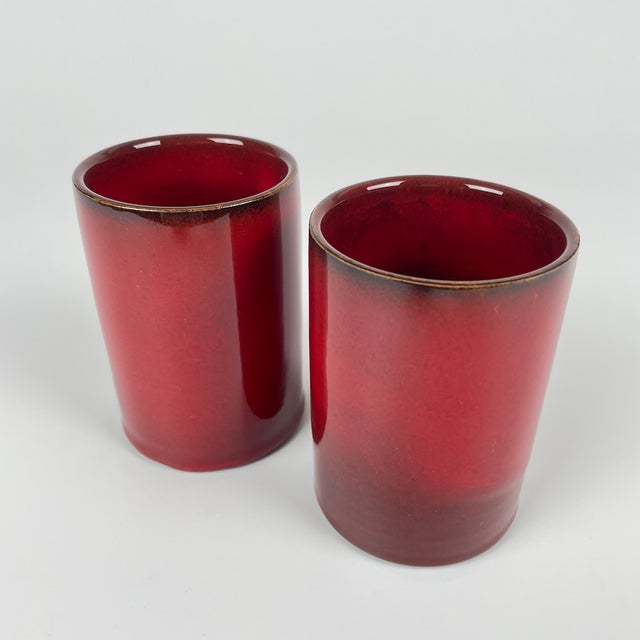 Pair of small, red-glazed ceramic roller vases with black accents on the neck and brown at the base, by Gérard Hoffmann....
