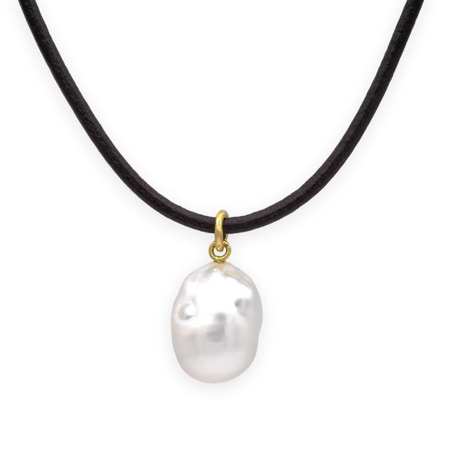 A beautifully organic and understated necklace pairing a large baroque South Sea-style pearl with a dark leather cord and...