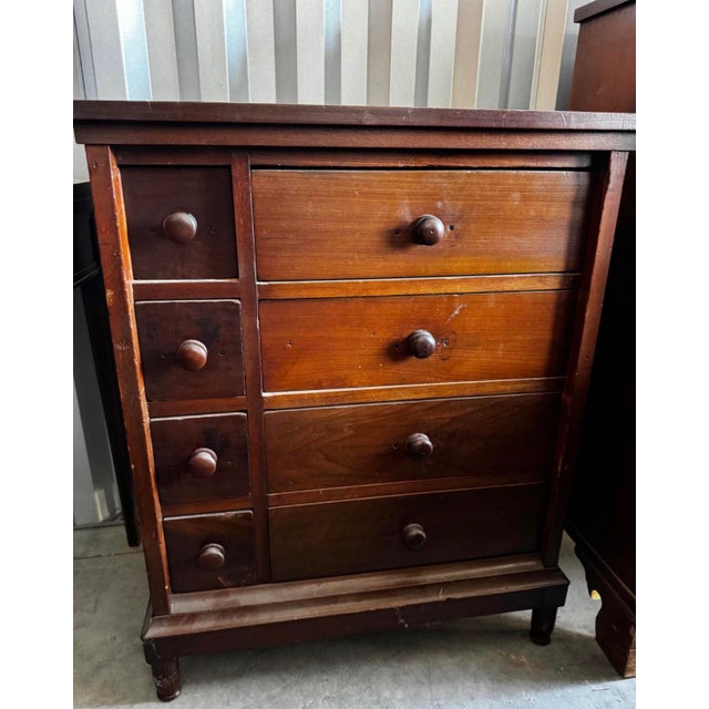 Traditional eight-drawer wooden chest featuring an asymmetric layout of four smaller drawers alongside four wider drawers....