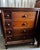 Traditional eight-drawer wooden chest featuring an asymmetric layout of four smaller drawers alongside four wider drawers....