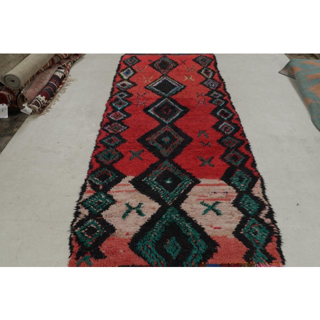 Originating from Morocco in the 1950s, this vintage midcentury Moroccan wool rug symbolizes strength, protection, and...