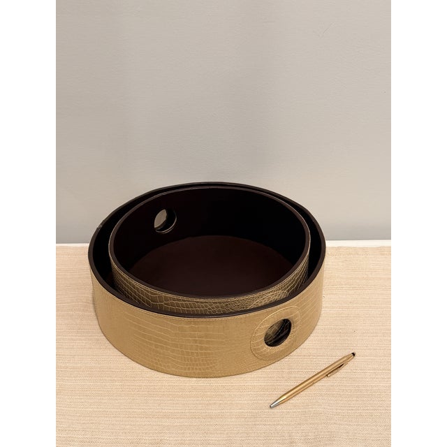 Elegant set of two nesting round trays wrapped in taupe faux crocodile embossed leather with rich chocolate brown...