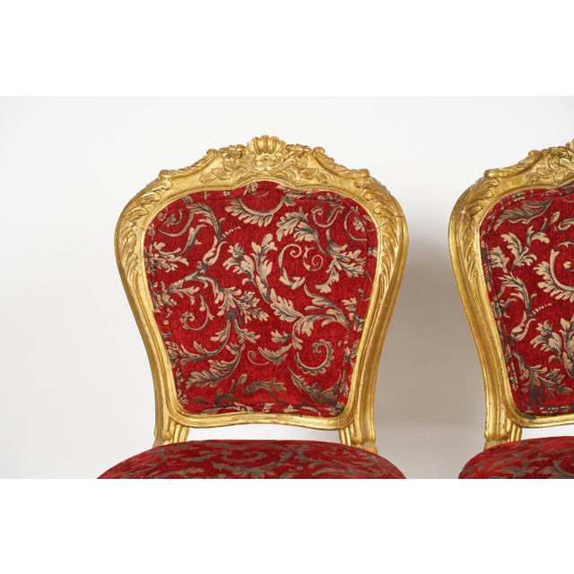 Beautiful pair of antique-style giltwood side chairs designed in the elaborate Louis XV Rococo Revival style, which...