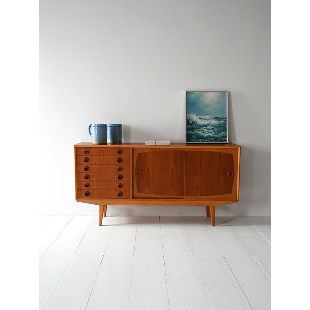 Sideboard in teak and oak with six drawers and two sliding doors. Round carved handles and double essence. Made between...